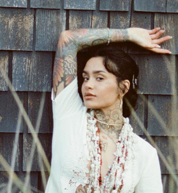 Kehlani poses against the wooden slats on a house 